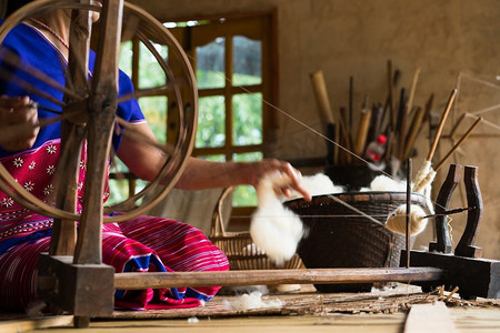 捏造摄影照片_在泰国清迈，工人在传统织布机上为羊毛服装和纱线原料工作的柔焦图像
