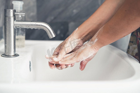 新型冠状病毒感染预防要点摄影照片_洗手预防新型冠状病毒病2019或新冠肺炎。人们在浴室洗手池洗手以清除病毒感染。