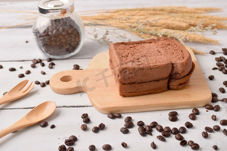 咖啡咖啡豆面包摄影照片_咖啡面包和咖啡豆早餐在木背景