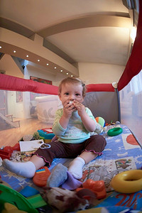 教育摄影照片_可爱的小婴儿玩玩具在移动床上使第一步和学习站立和行走