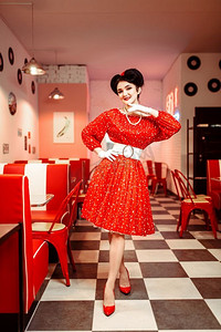 别针起来女人在红色礼服与白点，复古风格。复古咖啡厅内部与棋盘地板