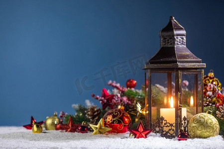 燃烧的圣诞灯笼和冷杉装饰在雪在蓝色背景与复制空间。圣诞灯在雪