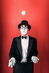 哑剧男演员与球杂耍。喜剧哑剧艺术家穿着西装，手套，眼镜，化妆面具和帽子。马戏团杂耍演员