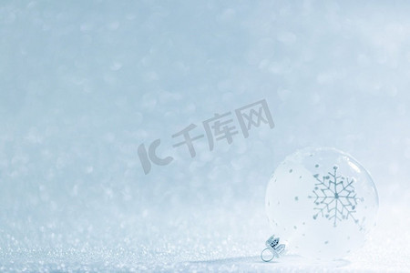 圣诞节标题框摄影照片_美丽的透明圣诞球，上面覆盖着节日闪闪发光的雪花背景。圣诞舞会在节日背景之上