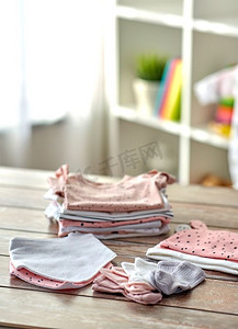 服装桌子摄影照片_婴儿和服装概念—婴儿衣服在木桌子在家里。婴儿衣服在木桌子在家里