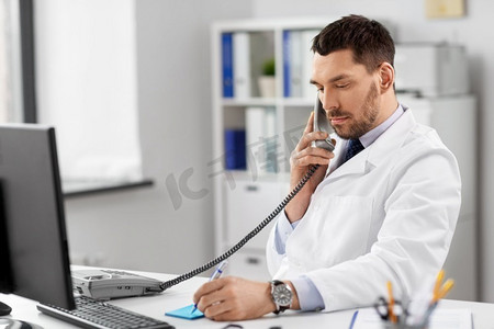 医疗、医学和人的概念-男医生在医院用剪贴板在台式电话上通话。男医生在医院用台式电话打电话