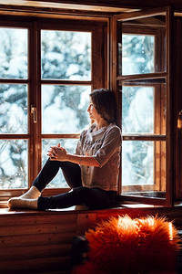 一个女孩在房子里靠近窗户俯瞰着一片雪景