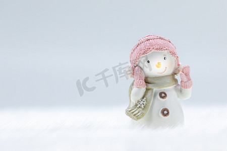 圣诞雪摄影照片_女性雪人玩具在冻结的雪轻冬天背景与副本空间。雪人玩具在冬季背景