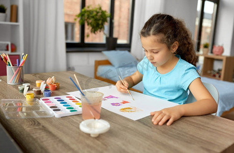 童年，爱好和休闲概念—小女孩在家里用颜色和画笔画画。小女孩与颜色绘画在家里