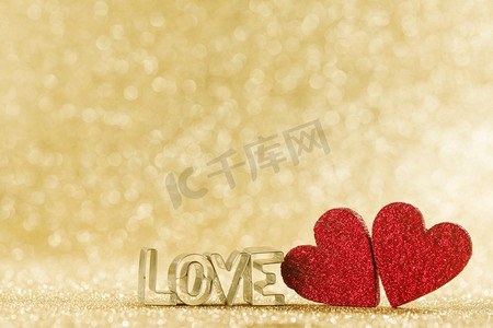 两个红色手工闪光的心和字爱在金色明亮的闪光灯bokeh背景。木心和字爱