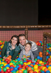 教育摄影照片_快乐的家庭享受自由时光年轻的父母和孩子在儿童游戏室的游泳池里玩五颜六色的球