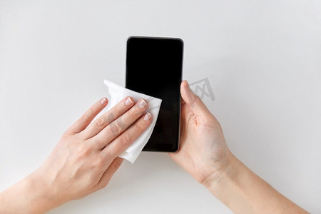 卫生和消毒概念—特写妇女手清洁智能手机与纸巾。近拍的手清洁智能手机与纸巾