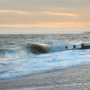 美丽的抽象长曝光风景图像波浪撞击到groynes在海滩在日落期间