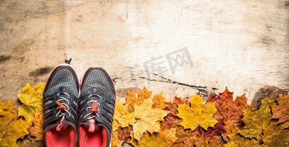 秋天的风格。秋叶上的运动鞋。在木质背景上..秋叶上的运动鞋。