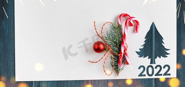 2022年圣诞节背景白色的纸与冷杉形状削减为新年2022卡在木桌。2022年圣诞或新年贺卡