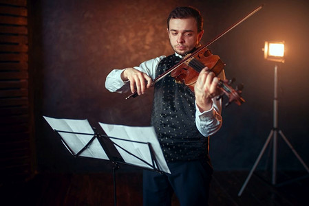 男性小提琴家的画象有小提琴反对音乐站有乐器演奏的小提琴手男子在演播室，独奏音乐会训练