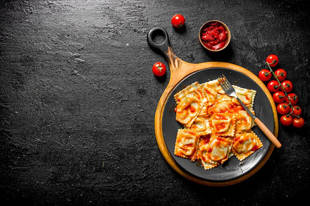 小饺子摄影照片_意大利饺子配小牛肉和番茄酱。在黑色的乡村背景上。意大利饺子配小牛肉和番茄酱。