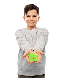 生态生活，环境和可持续发展的概念-微笑的男孩在白色背景上举着绿色的房子图标。微笑的男孩手持温室标志