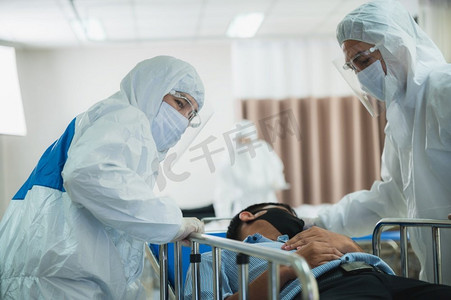 身穿全套防护服、戴着外科口罩的专业医生正在医院控制区对感染患者进行检查，