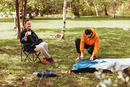 露营，旅游和旅行概念—愉快的夫妇设置帐篷户外。快乐的夫妇设置帐篷户外