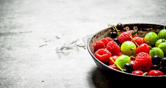 石原里美摄影照片_旧盘子里的野浆果。在石桌上。旧盘子里的野浆果。在石桌上。