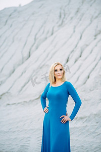 火车与女孩摄影照片_金发女郎在一件蓝色连衣裙与蓝色眼睛在一个花岗岩采石场反对砾石的背景