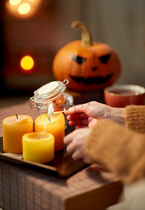 假日和休闲概念—妇女的手与火柴点燃蜡烛在家里万圣节。’手与火柴点燃蜡烛在万圣节