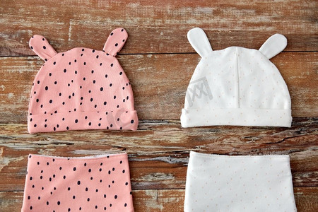 婴儿时期和服装概念—婴儿帽子与耳朵和围兜在木桌子上。婴儿帽与耳朵和围兜在木桌子上