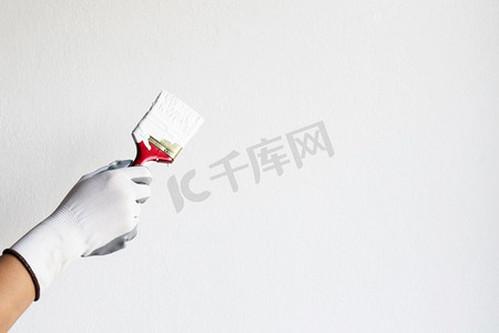 粉底液贴纸摄影照片_油漆工正在家里卧室的墙上涂白色的粉底。