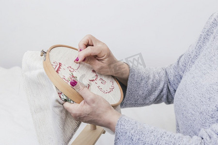 刺绣服装摄影照片_妇女的手交叉缝合模式在一个箍对白色背景