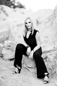 金发女郎在一个黑色裤子西装与蓝色眼睛在花岗岩采石场的背景从灰色瓦砾