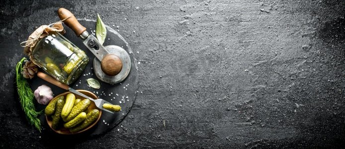 自制腌制黄瓜在石头板。在黑色的乡村背景。自制腌制黄瓜在石头板。