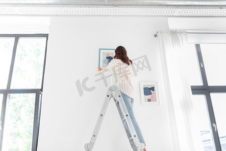 设计师海报摄影照片_家装、装修与人的理念--幸福微笑的女人站在梯子上用艺术装饰家。梯子上的女人用艺术装饰家