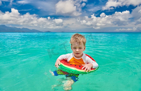 塞舌尔海滩上三岁蹒跚学步的男孩戴着充气环游泳