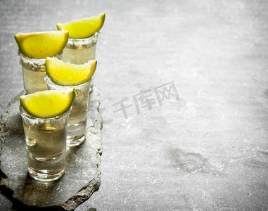 龙舌兰酒摄影照片_龙舌兰酒加酸橙和盐。在石桌上..龙舌兰酒加酸橙和盐。