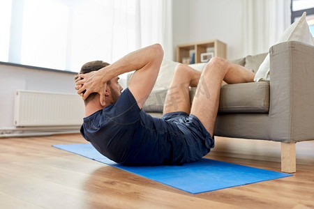 运动，健身和健康生活方式概念—男子在家里做腹部运动。男人做腹部运动在家里