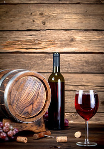 桶，一瓶和一杯红酒。在一个木制的背景。.桶，一瓶和一杯红酒。 