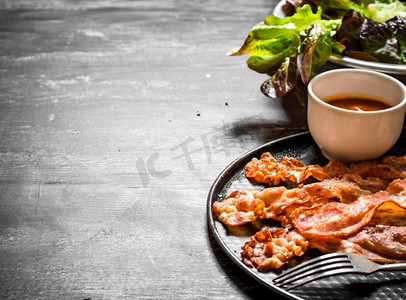 咸肉摄影照片_炒咸肉配酱汁和蔬菜。在一个黑色的木背景。炒咸肉配酱汁和蔬菜。