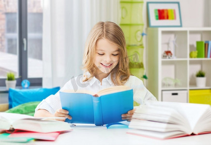 教育和学校概念—愉快的微笑的学生女孩读书在家庭背景快乐的微笑的学生女孩读书在家