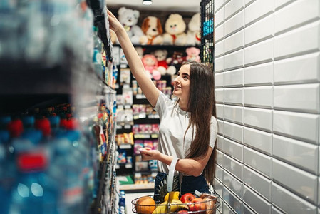 食品店里推着手推车的女顾客。女人在杂货店购物，在市场上买东西。食品店推着手推车的女顾客