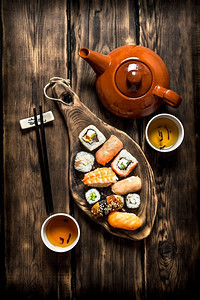 寿司和面包卷配花草茶。在一张木桌上。寿司和面包卷配花草茶。