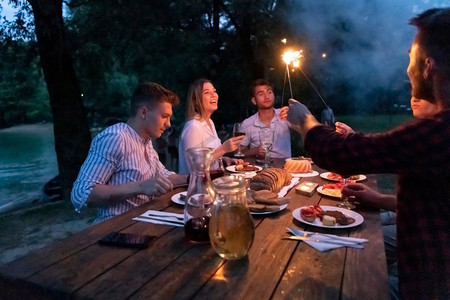一组愉快的朋友野餐法国晚餐聚会户外在暑假假期在美丽的自然附近的河