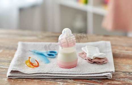 装东西摄影照片_婴儿期概念-装婴儿奶粉的瓶子和家里木桌上的东西。装婴儿配方奶粉的瓶子和桌上的东西