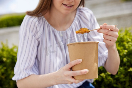 特写妇女吃健康的素食或素食汤作为外卖午餐从可回收包装与木制勺子