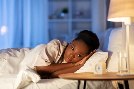 人、就寝时间和休息的概念--非洲裔美国妇女晚上躺在床上睡不着觉。夜里躺在床上的不眠非洲妇女