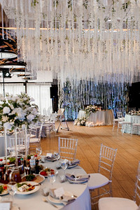 宴会厅摄影照片_餐厅宴会厅的新婚夫妇主席团用蜡烛和绿色植物装饰，紫藤从天花板上垂下来