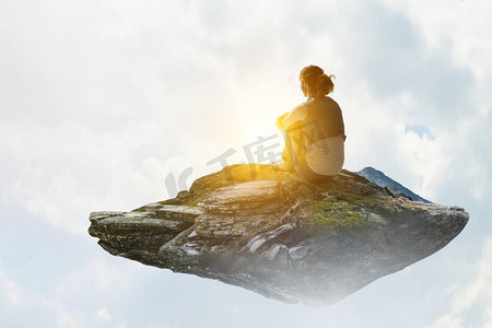 穿着休闲服的年轻女子坐着抱膝的背影.工艺品佛像