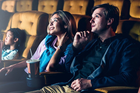 一对夫妇和孩子在电影院里享受和随意地看电影，