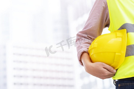 托管班招生啦摄影照片_身着安全服托管队的建筑工程师戴着白黄色安全安全帽
