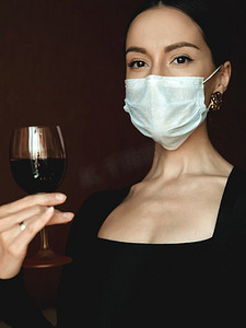 流行创意摄影照片_戴着医用口罩和葡萄藤的年轻美丽女士的生活写真。呆在家里。冠状病毒。隔离。世界冠状病毒大流行